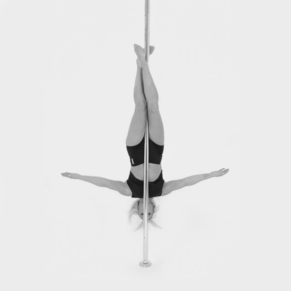 One woman holding a crucifix pose during a pole fitness class at The Pole Hub