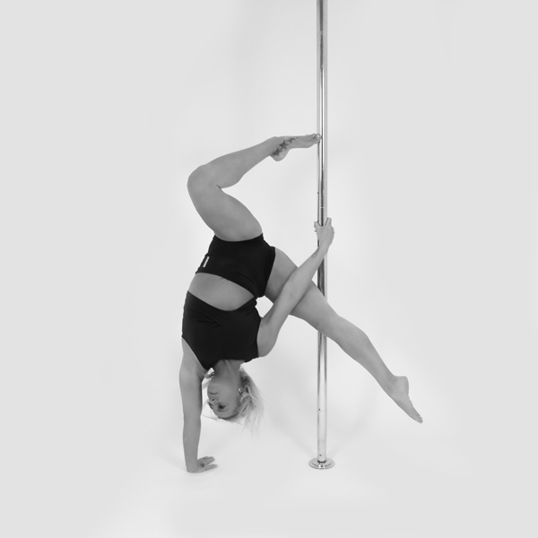 One woman holding a geni hand stand pose during a pole fitness class at The Pole Hub