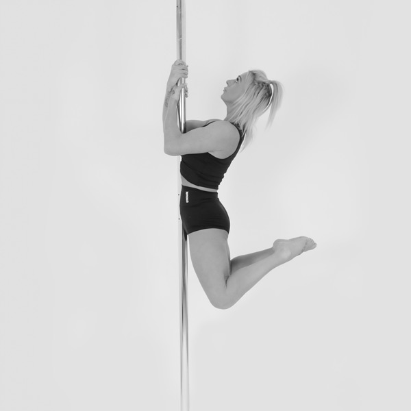 One woman holding a kneeling slide pose during a pole fitness class at The Pole Hub