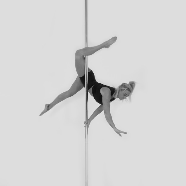 One woman holding an eros pose during a pole fitness class at The Pole Hub
