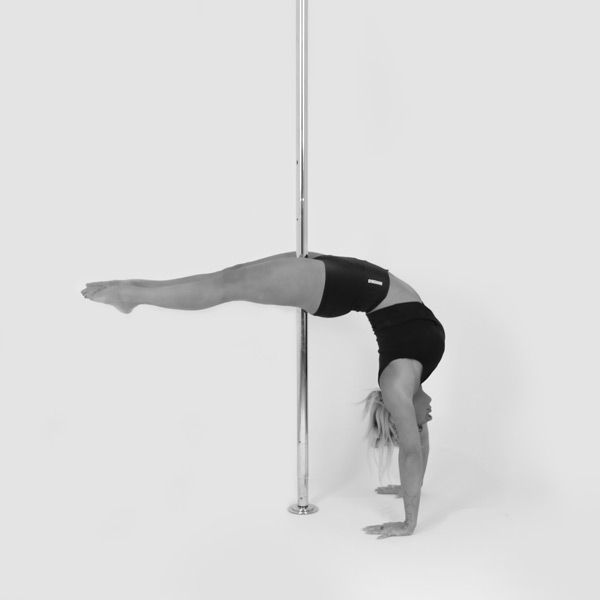 One woman holding a crescent moon handstand pose during a pole fitness class at The Pole Hub