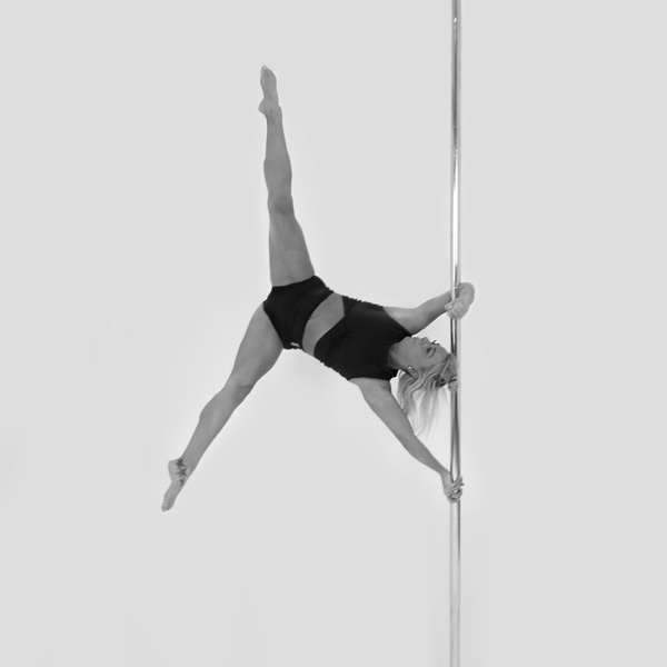 One woman holding a iron-x pose during a pole fitness class at The Pole Hub