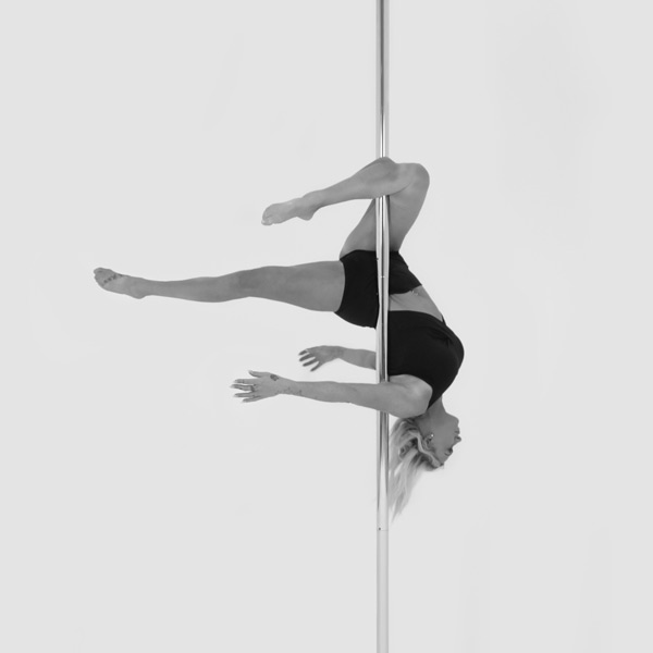 One woman holding a gemini pose during a pole fitness class at The Pole Hub