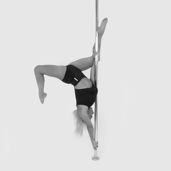 One woman holding a butterfly pose during a pole fitness class at The Pole Hub