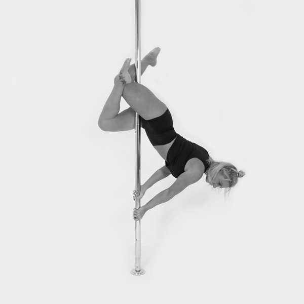 One woman holding a cross thigh hold pose during a pole fitness class at The Pole Hub