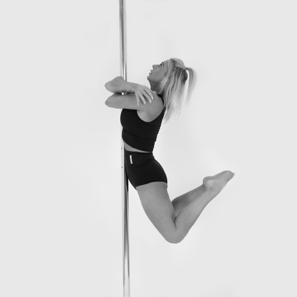 One woman holding an embrace pose during a pole fitness class at The Pole Hub