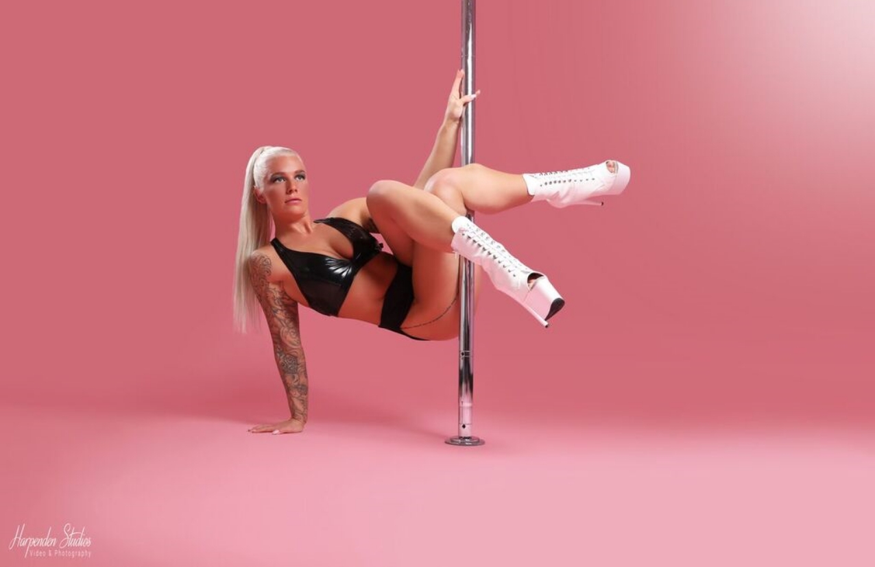 One woman holding a pose during a pole dance class at The Pole Hub