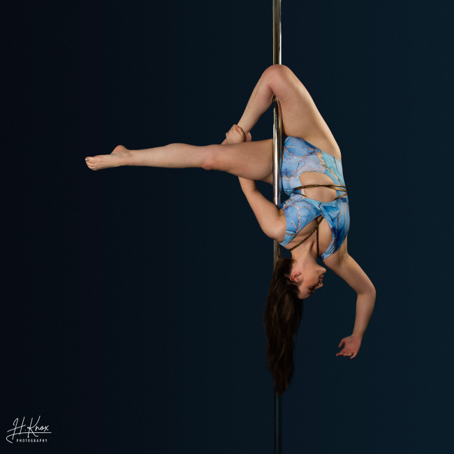 Instructor Daisy R holding a pose during a pole fitness class at The Pole Hub