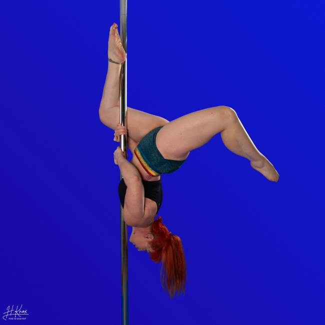 Instructor Dominique P holding a pose during a pole fitness class at The Pole Hub