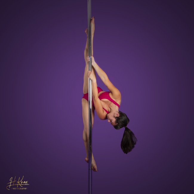 The Pole Hub instructor Lara P holding a pose on a pole