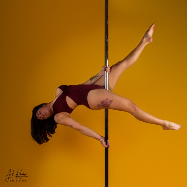 Instructor Lara P holding a pose during a pole fitness class at The Pole Hub