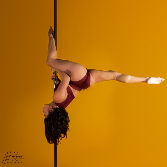 Instructor Lara P holding a pose during a pole fitness class at The Pole Hub